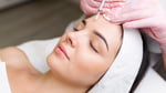 Close up of hands of cosmetologist injecting botox in female face